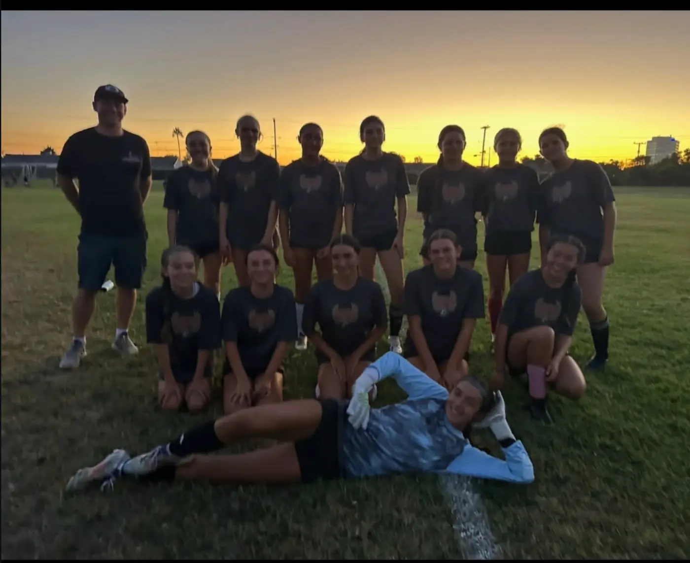 The squad lined up for a photo on the field at sunset